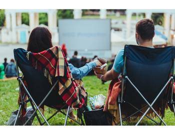 Waterfront Music and Movies couple watching movie on projector in grass