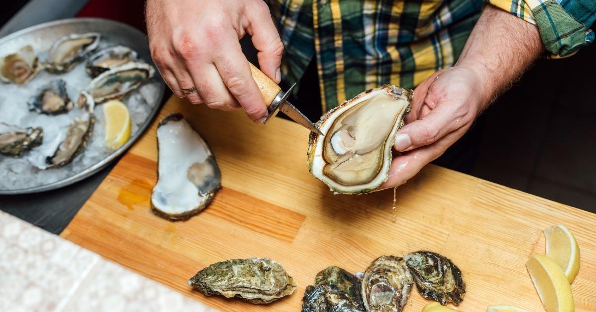 man shucking raw oyster